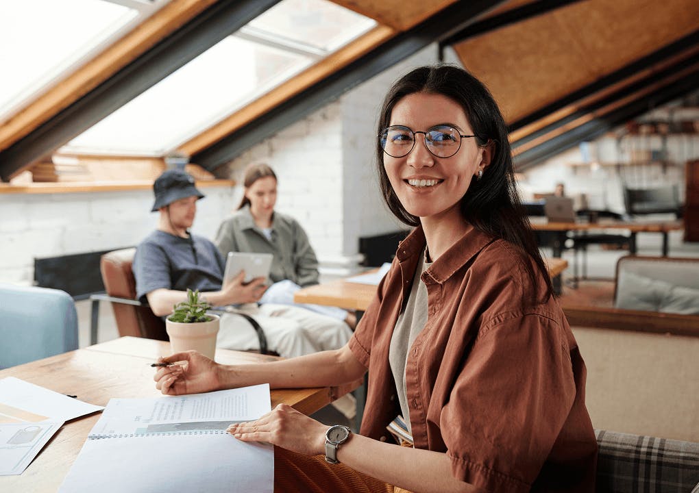 Startup CEO sits in her office with colleagues in the background