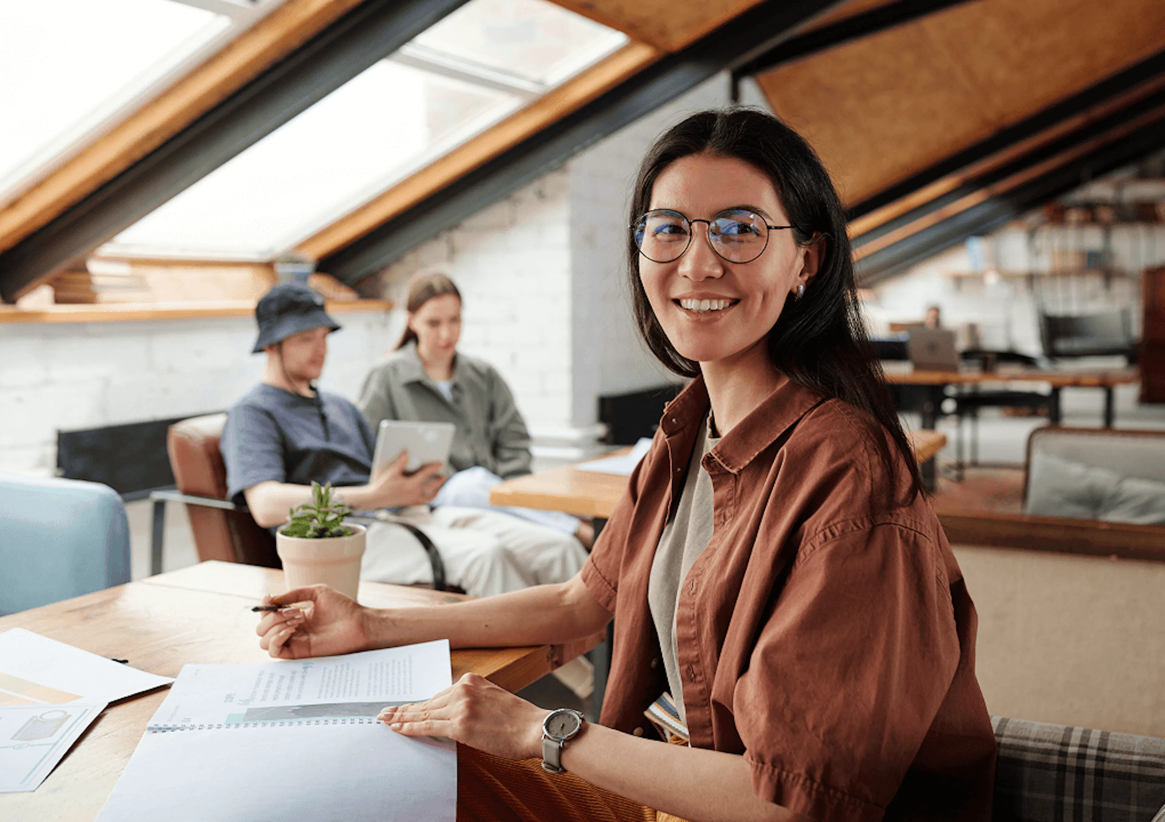 Startup CEO sits in her office with colleagues in the background