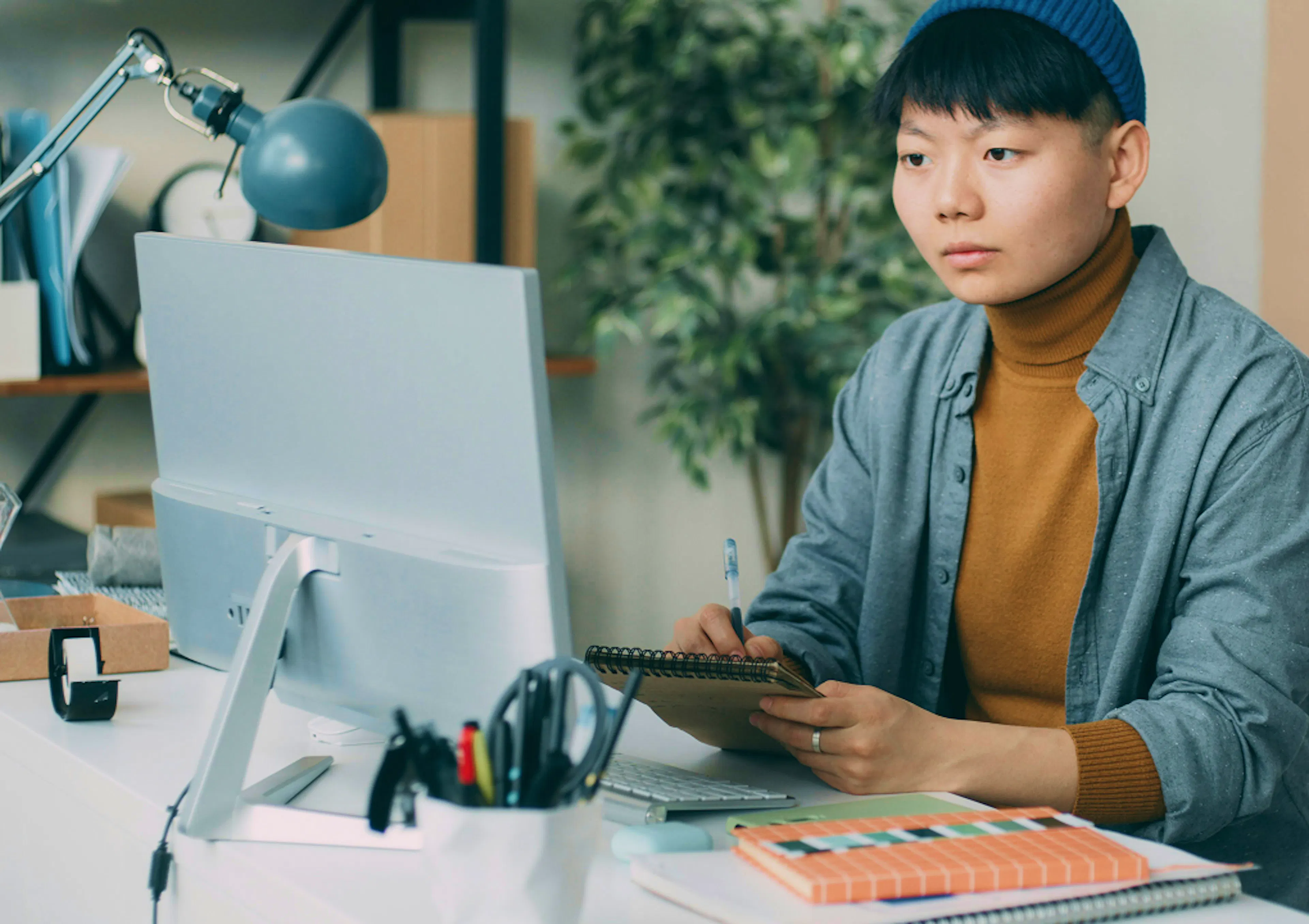 Office worker sits facing us, looking at a desktop screen