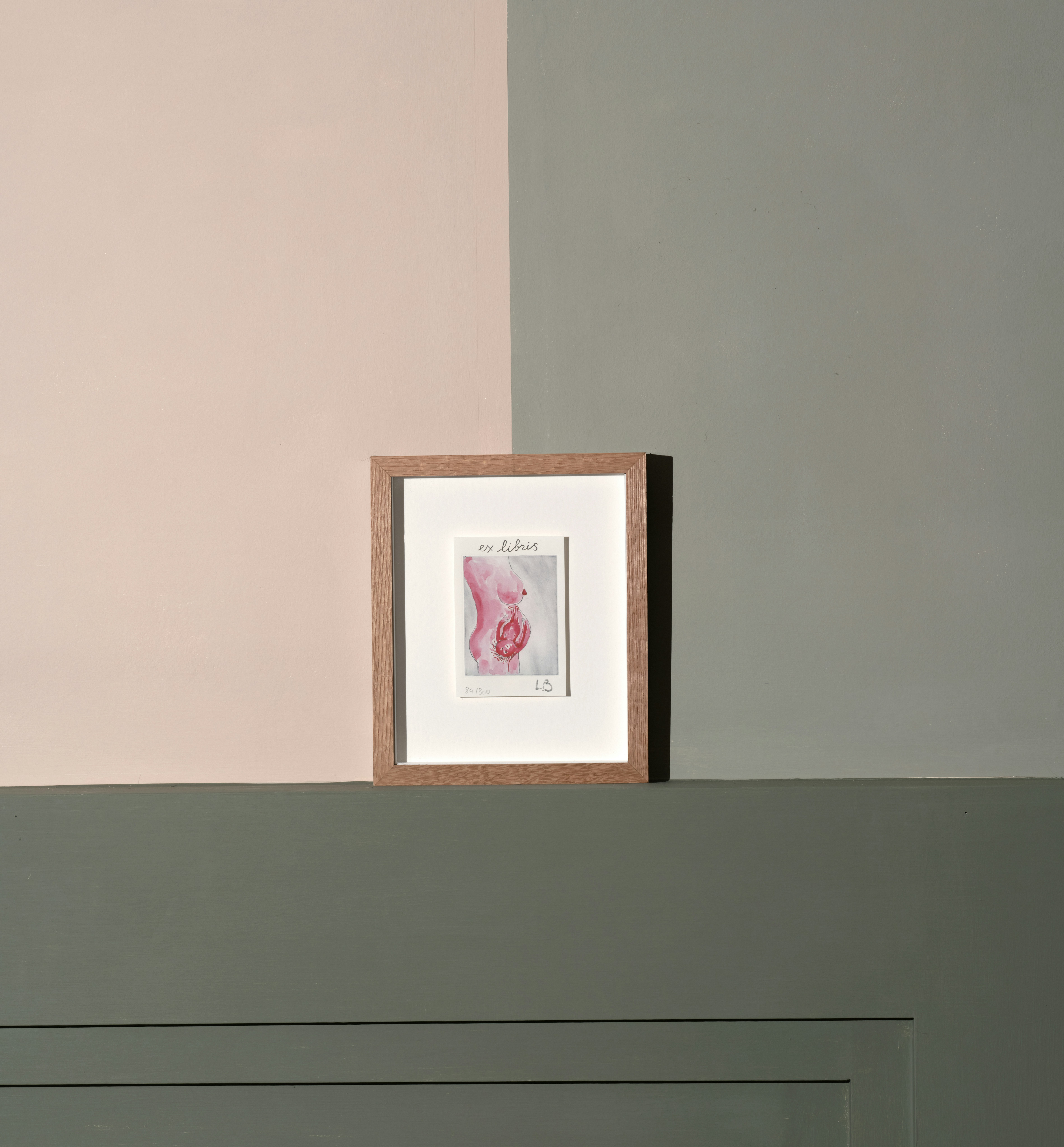 Installation photo of framed lithograph by Louise Bourgeois depicting a cropped image of female pregnant nude in profile, child in womb visible on grey background.