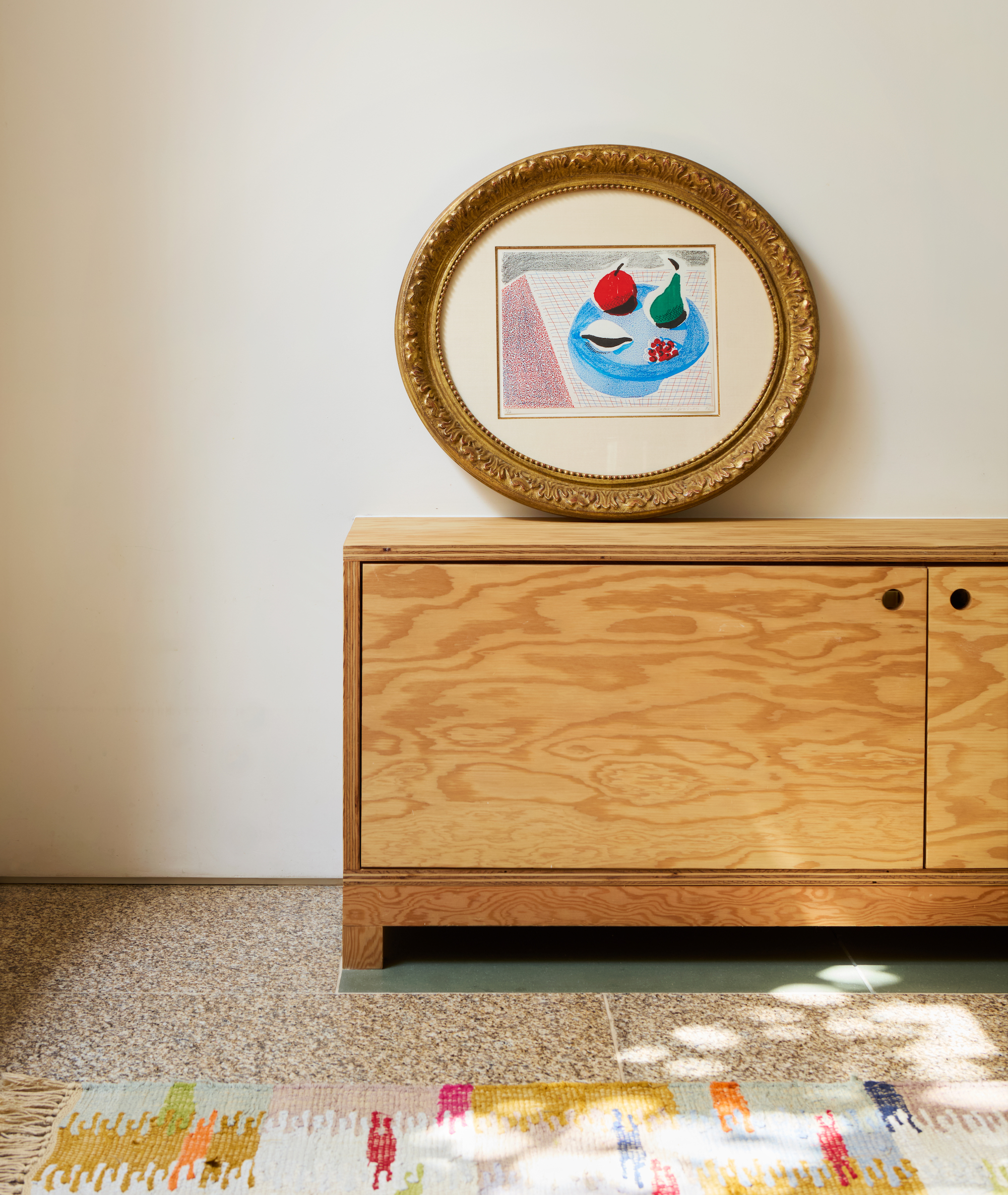 David Hockney Round Plate homemade print in a gilded frame leaning on sideboard.