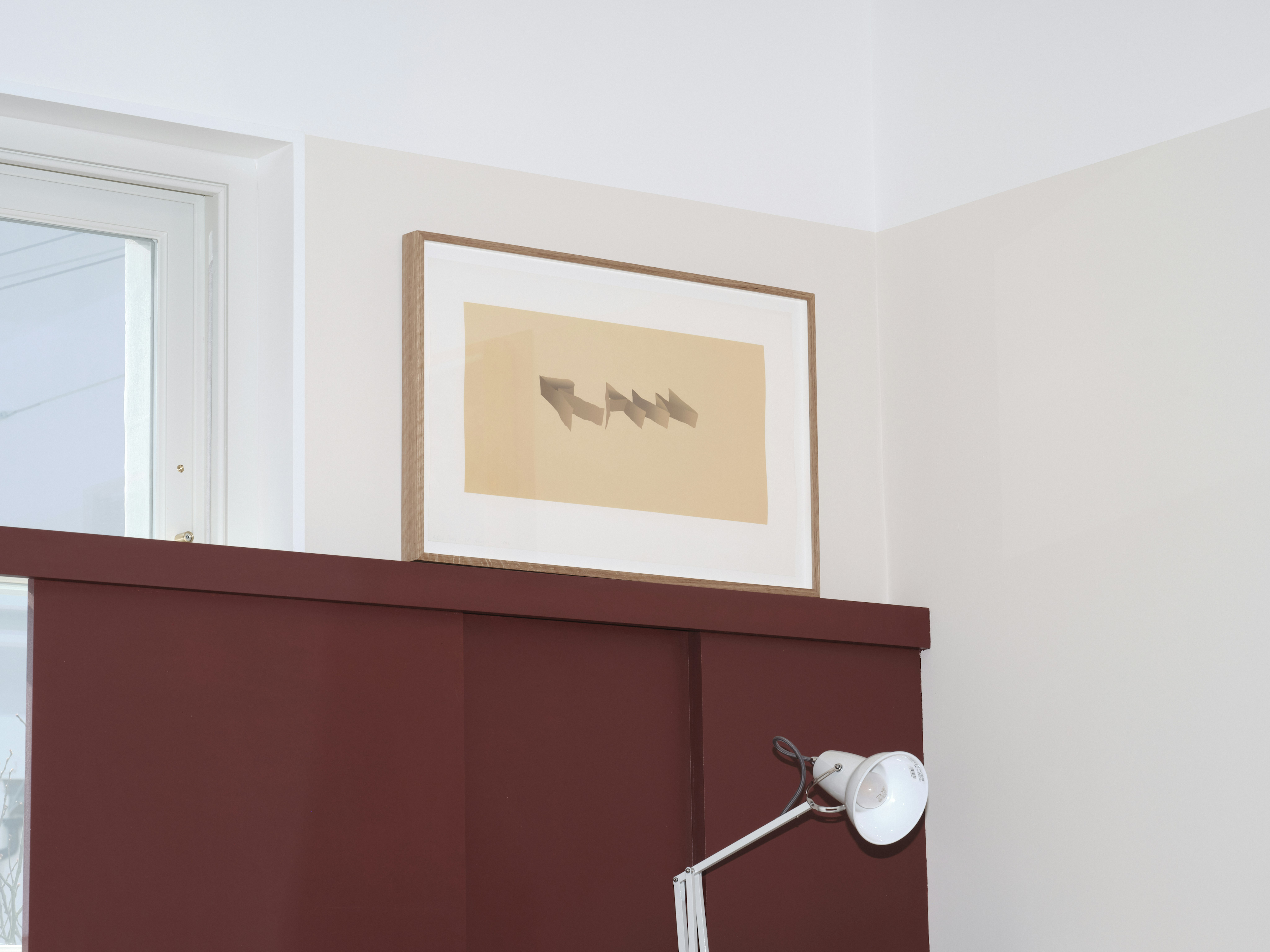 installation photograph of framed screenprint by Ed Ruscha in mustard yellow overlaid with the word raw in capital letters in perspective and slightly skewed in darker tone brown-yellow