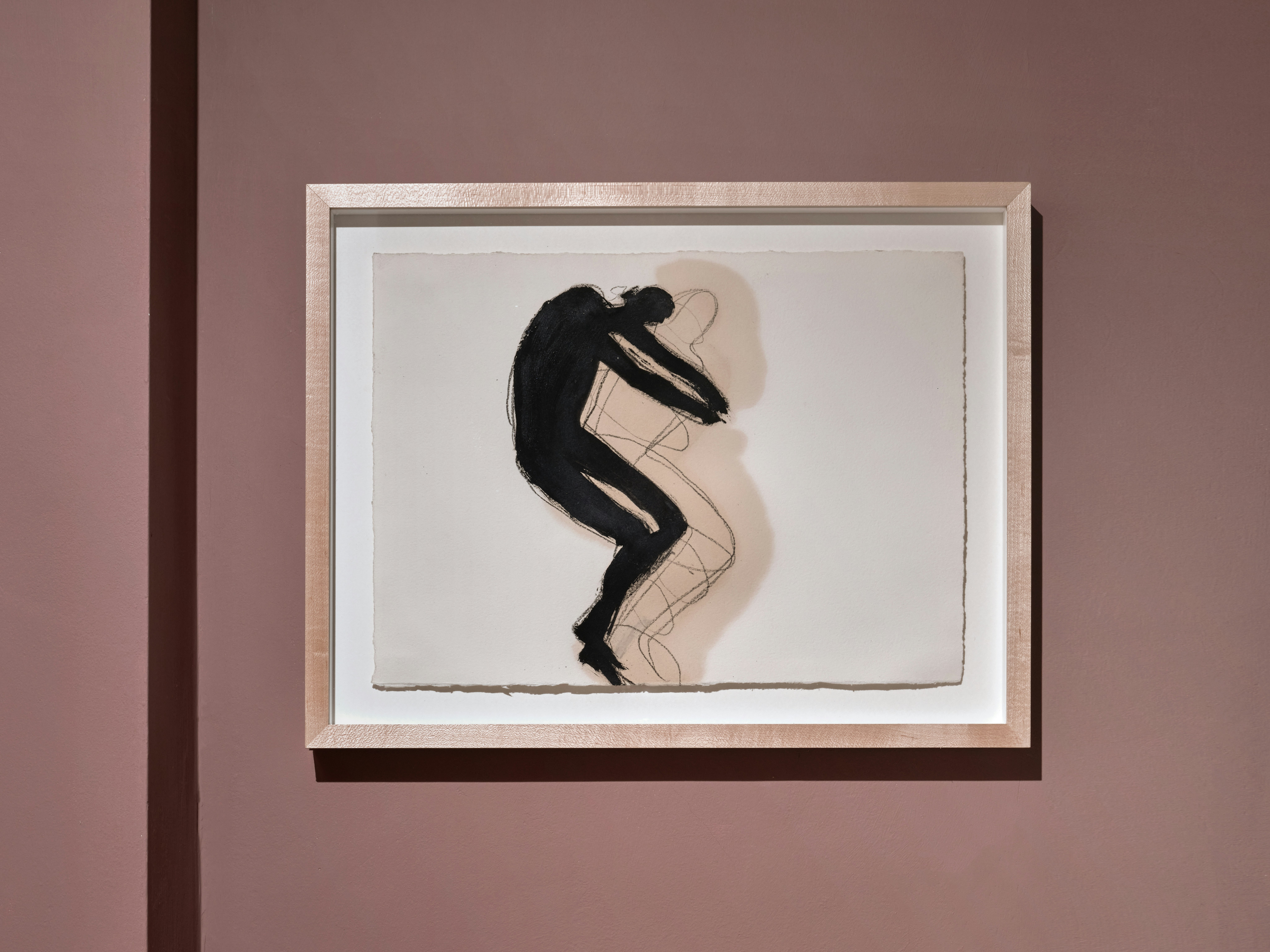 Installation photo of framed drawing by Antony Gormley made with black pigment, linseed oil & charcoal depicting figure of man laying sideways and their shadow