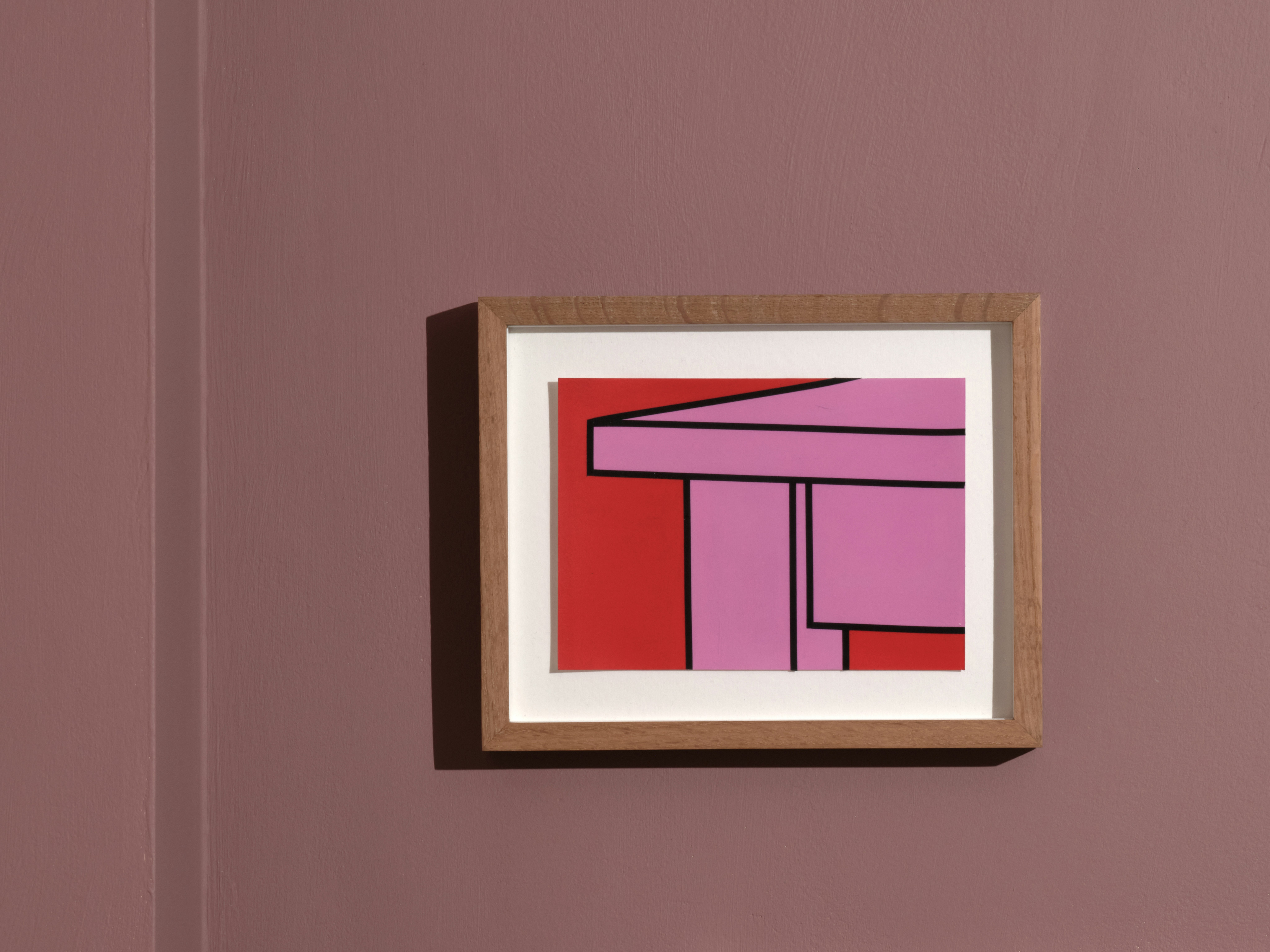 Installation photo of framed collage drawing by Michael Craig-Martin depicting a pop-coloured table in pink with black outline on bright red background.