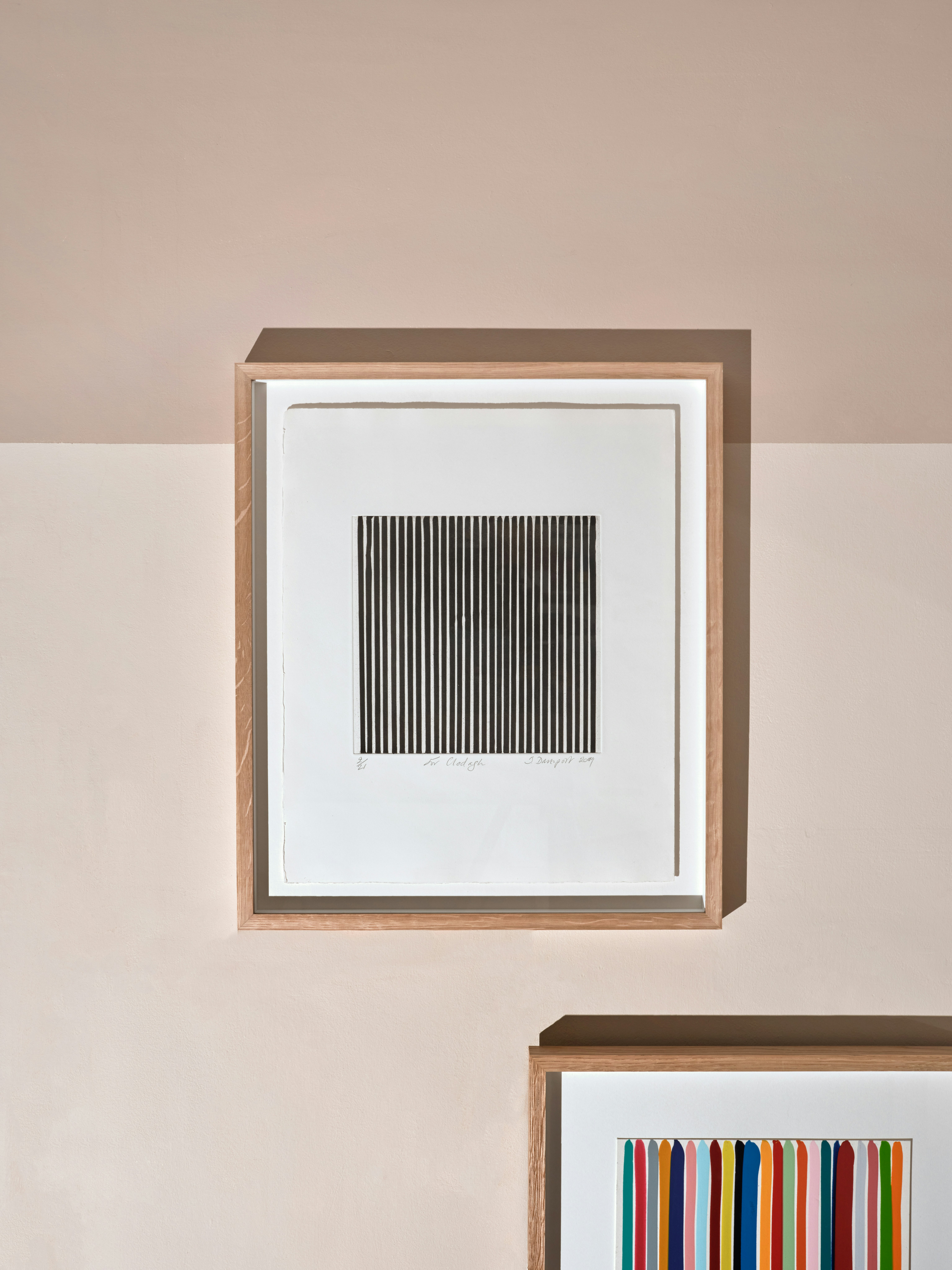 Composite installation shot of two framed works by Ian Davenport, etching with aquatint in black depicting the artist’s signature vertical poured lines, the other one acrylic with water-based paints depicting drip of multi colour vertical lines across sheet.