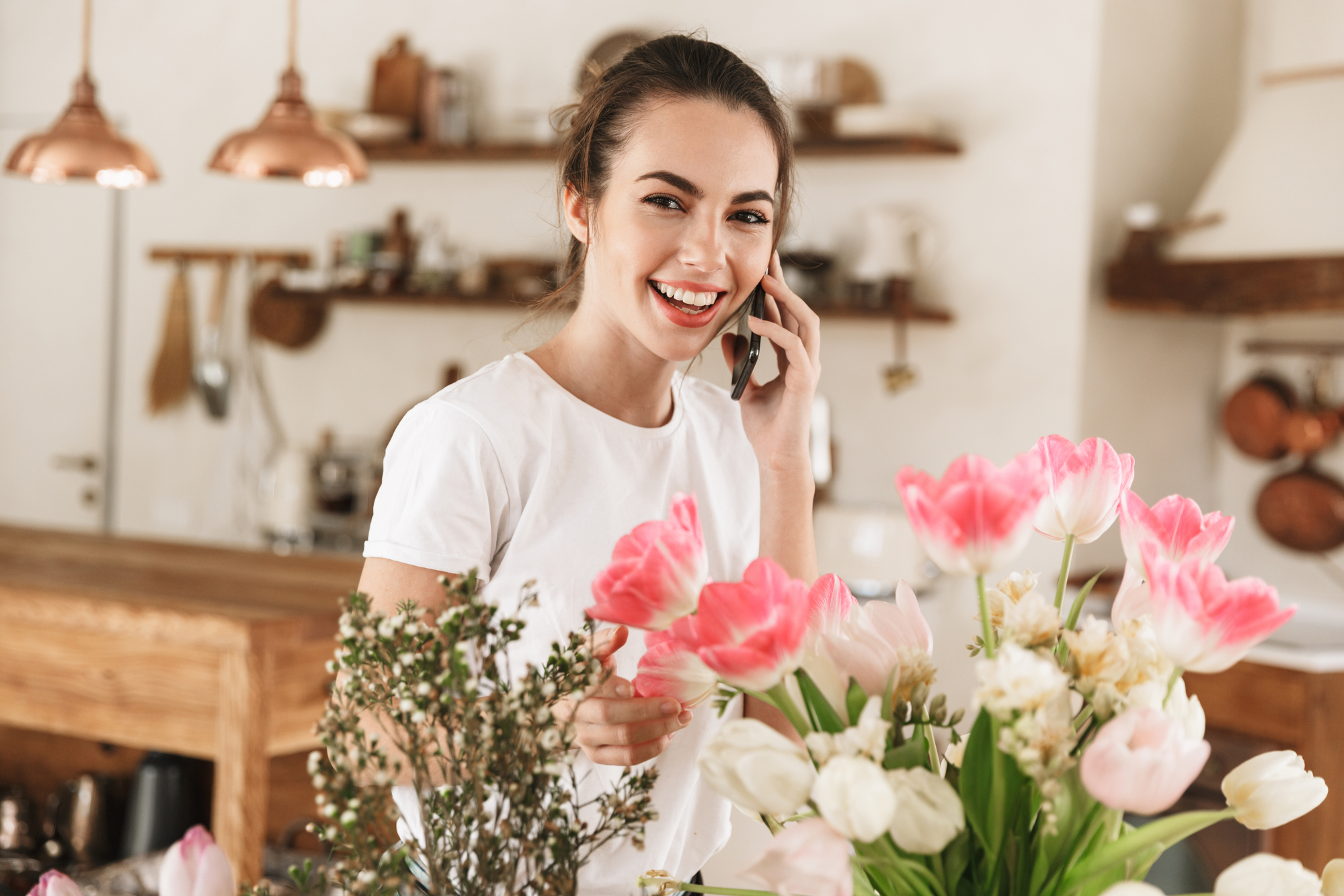 Jonge lachende vrouw die aan de telefoon is met een boeket op de voorgrond