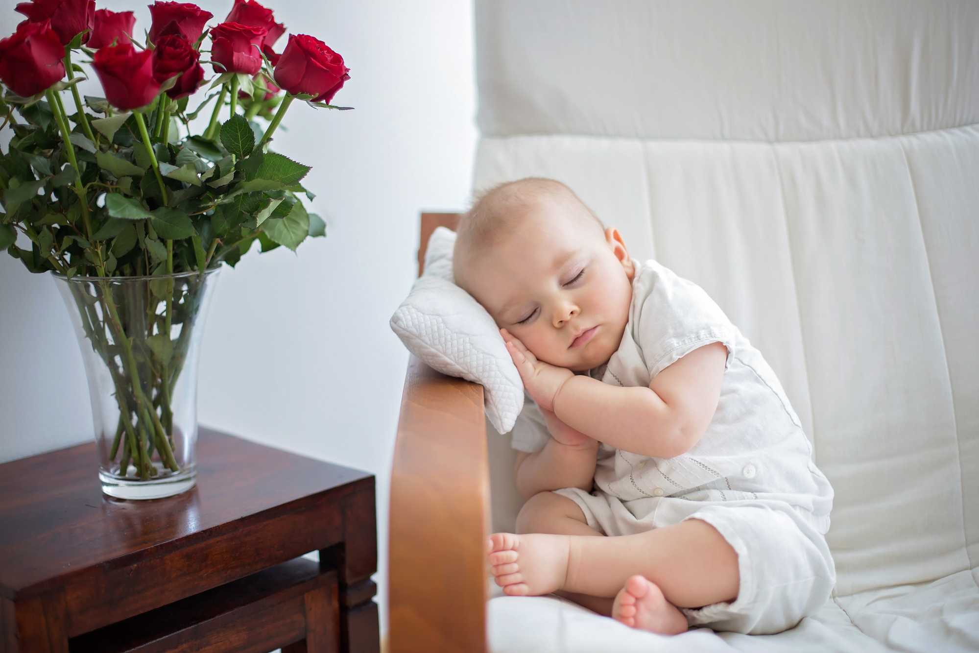 Baby die in stoel slaapt naast een boeket rozen in vaas