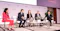 A panel discussion at a Reuters event, with five individuals seated on stage. The backdrop features the Reuters logo and the hashtag #ReutersNEXT. The participants are dressed in formal business attire and appear to be engaged in a professional dialogue. There are plants and a table with documents and a microphone in front of them, suggesting a structured and organised setting for the discussion.