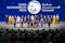 The image depicts a group of individuals on stage holding awards at the Zayed Sustainability Prize ceremony. The event appears to be formal, with attendees dressed in a mix of traditional and business attire. The backdrop displays the name of the prize in both English and Arabic, indicating the event's focus on sustainability and international participation.