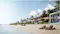 Luxury beachfront villas on Palm Jebel Ali, a man-made island in Dubai, UAE. These villas feature modern architecture, expansive glass facades, and are surrounded by lush palm trees. They provide direct access to a private beach, with sun loungers and umbrellas set up on the sand, all against the backdrop of clear blue waters, exemplifying Dubai's high-end residential developments.