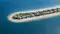 The image depicts a frond of Palm Jebel Ali, a man-made island development in Dubai, UAE. It showcases a series of luxury beachfront villas lined along the frond, surrounded by clear blue waters. The setting reflects a high-end residential area with private beach access, lush greenery, and modern architectural designs, typical of Dubai's ambitious real estate projects.