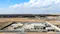 A green hydrogen project facility situated in a desert landscape. The facility appears to be part of a larger renewable energy complex, possibly utilizing solar power to produce hydrogen fuel. The infrastructure includes several buildings and structures, surrounded by a fenced perimeter, indicating a secure and controlled environment for green hydrogen production. This project highlights the integration of advanced technology and sustainable practices to generate clean energy, contributing to efforts in reducing carbon emissions and promoting environmental sustainability.