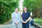 The image features her standing outside with a man in a light grey suit, both posing for the camera in a leafy campus setting. The overall context suggests academic or professional activities taking place at a university.