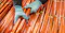 The context is industrial manufacturing or materials processing, specifically related to copper. The image shows a person wearing blue gloves handling multiple copper rods or bars, which are neatly arranged and labeled. This suggests activities such as quality control, sorting, or preparation of copper materials for use in electrical, construction, or industrial applications.