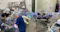 This image shows a laboratory or medical setting where several individuals are working with specialized equipment. They are using isolation chambers with built-in gloves, likely to handle sensitive or hazardous materials in a sterile environment. The workspace is equipped with various medical and laboratory supplies, indicating a focus on safety and precision. The scene suggests procedures related to infection control, research, or medical treatment requiring containment.