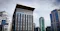 A modern high-rise building labeled "TERA TOWER MASLAK" stands prominently in the center, surrounded by other office and residential towers under a cloudy sky. A Turkish flag is visible on a lower rooftop in the foreground, with distant hills and city buildings in the background.