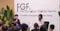 Audience seated at a conference forum, listening to a moderated discussion on stage. Two speakers sit in chairs in front of a backdrop reading “FGF FinCity.Tokyo Global Forum Leaders Session New York,” with large green plants on either side and a small table between the speakers.