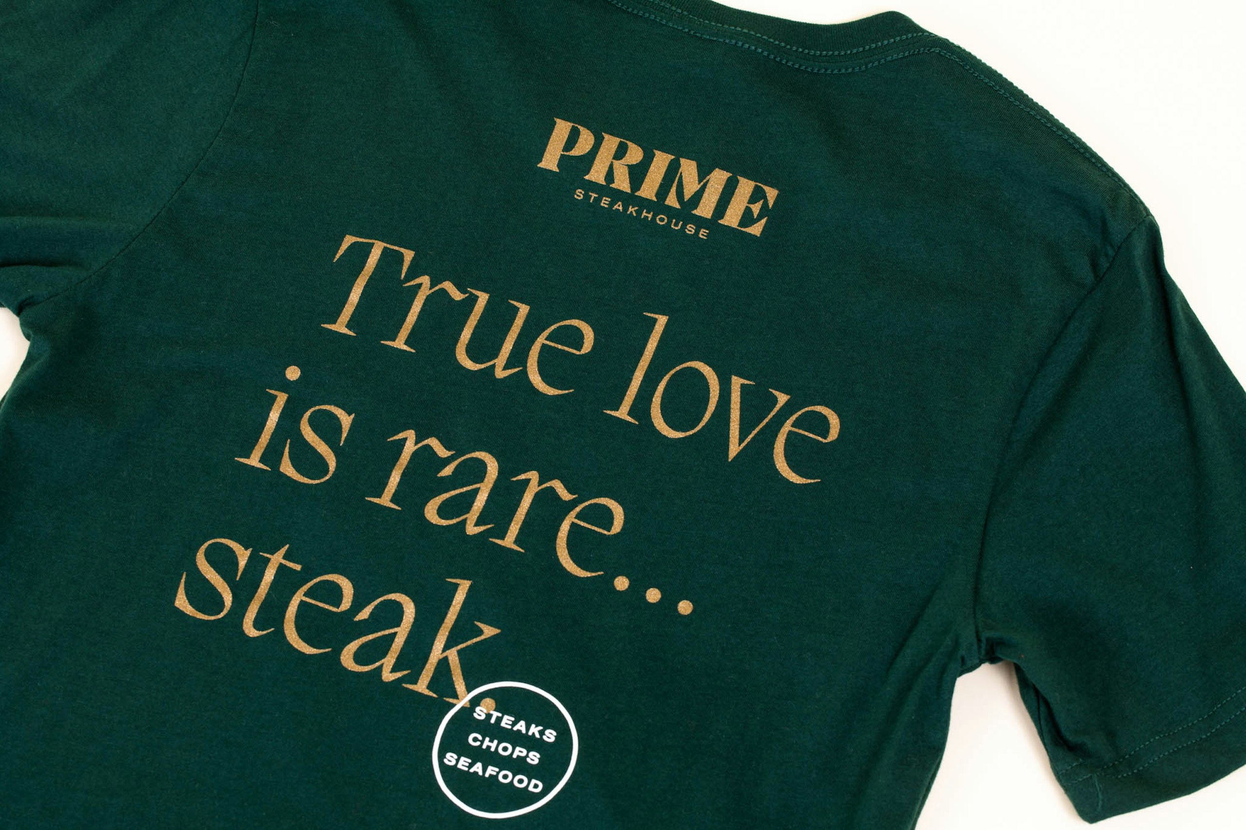A green shirt with gold metallic ink that says "True love is rare...steak" 