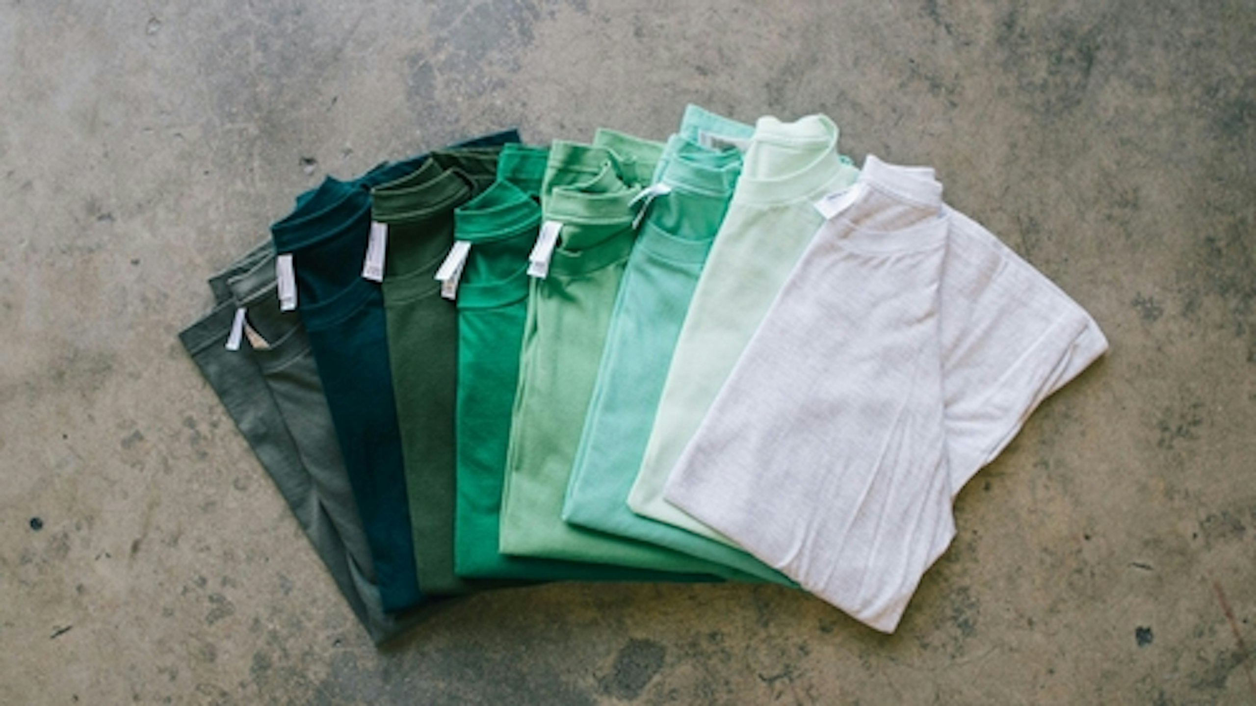 a collection of green shirts from white to dark green