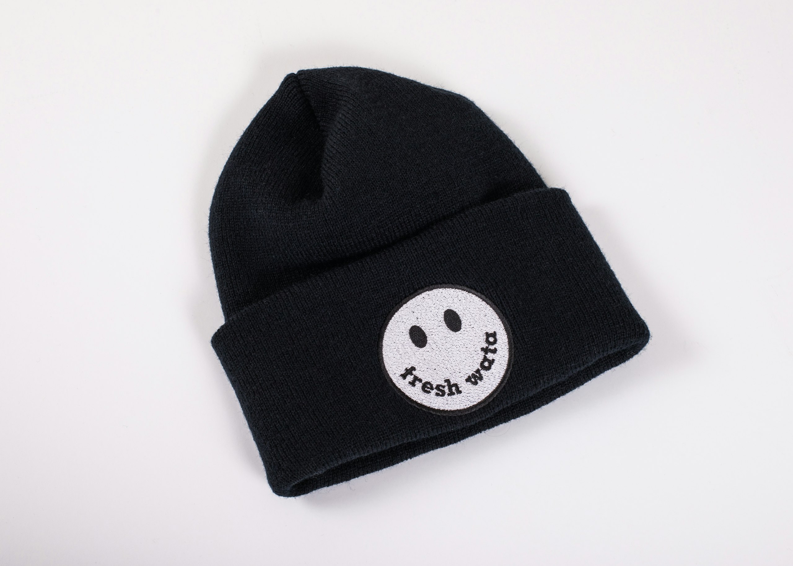 A black beanie that has an embroidered design that says "fresh wata" in a smiley face.