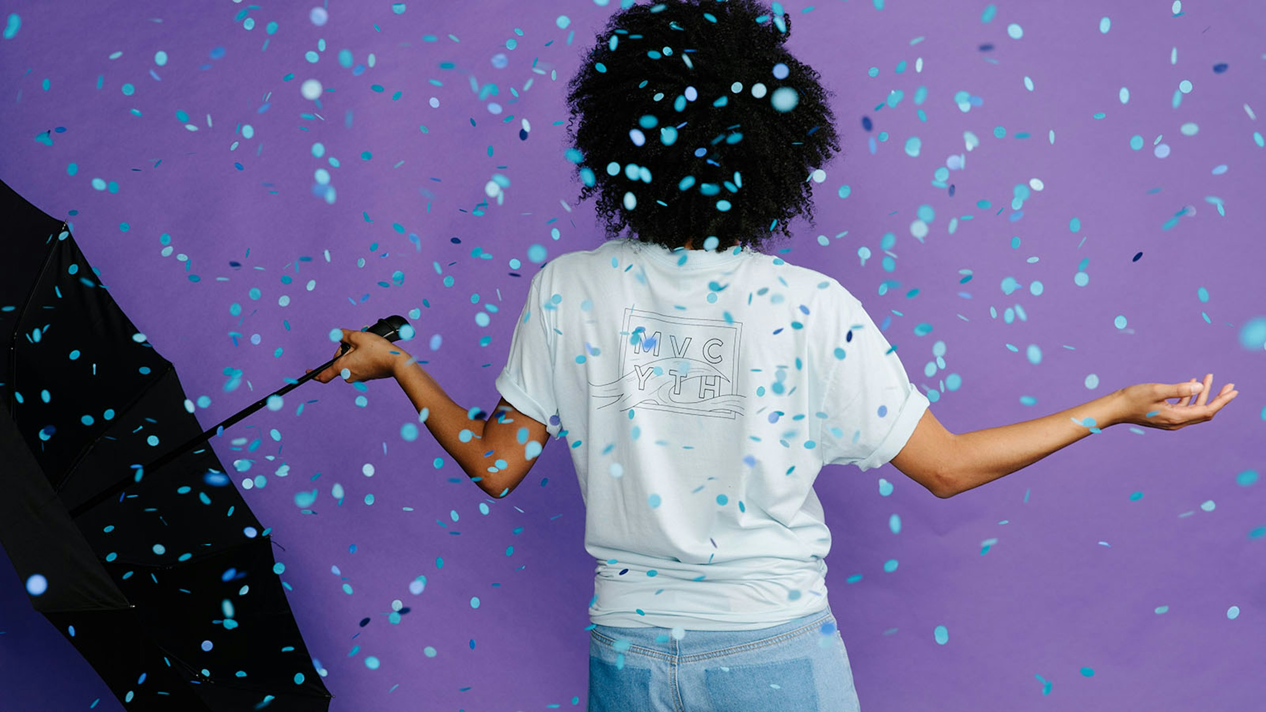 women with an umbrella in front of a purple background with blue confetti falling
