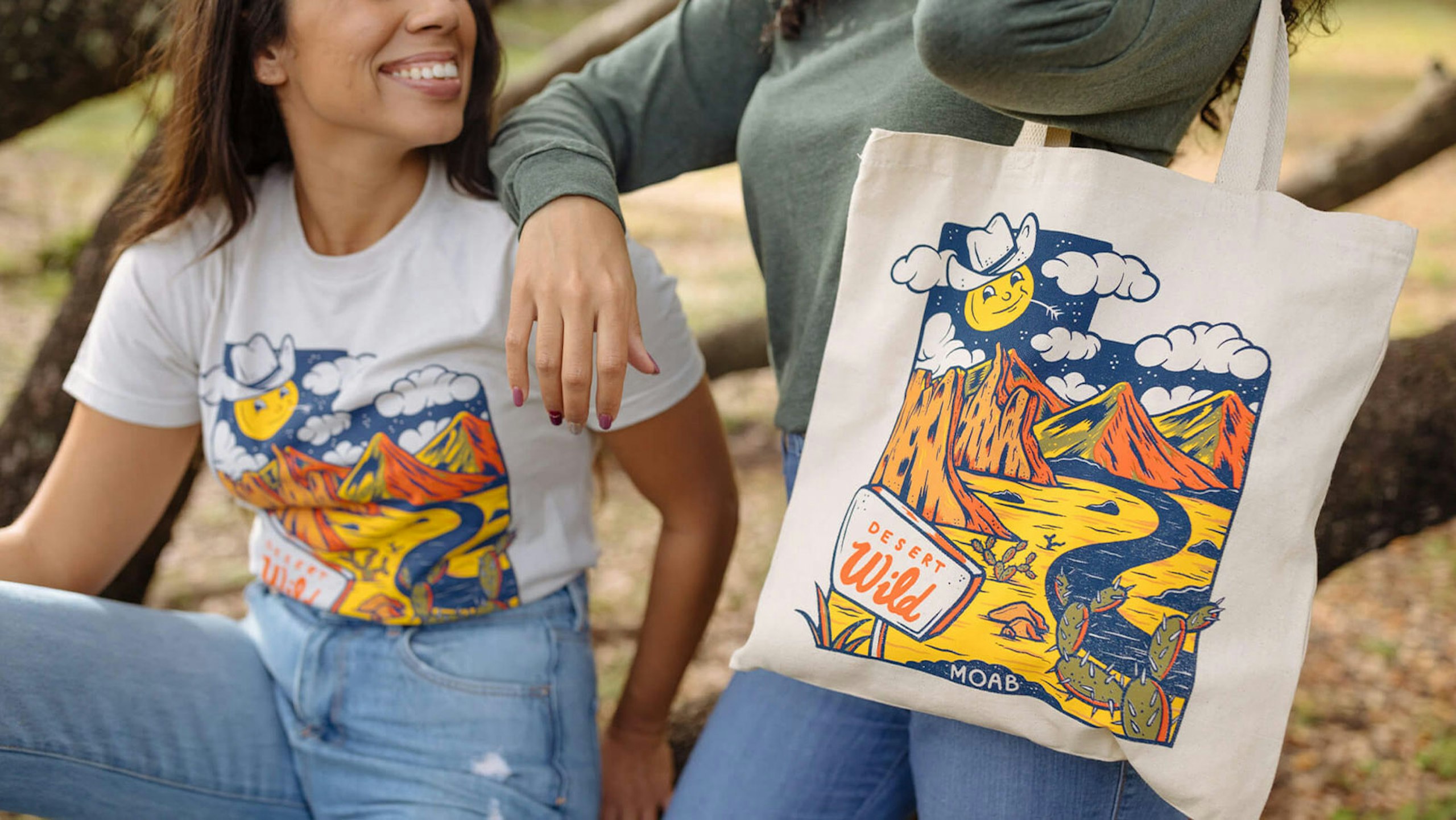 two women, one with a white shirt with a creative design—one with a tote bag with the same design