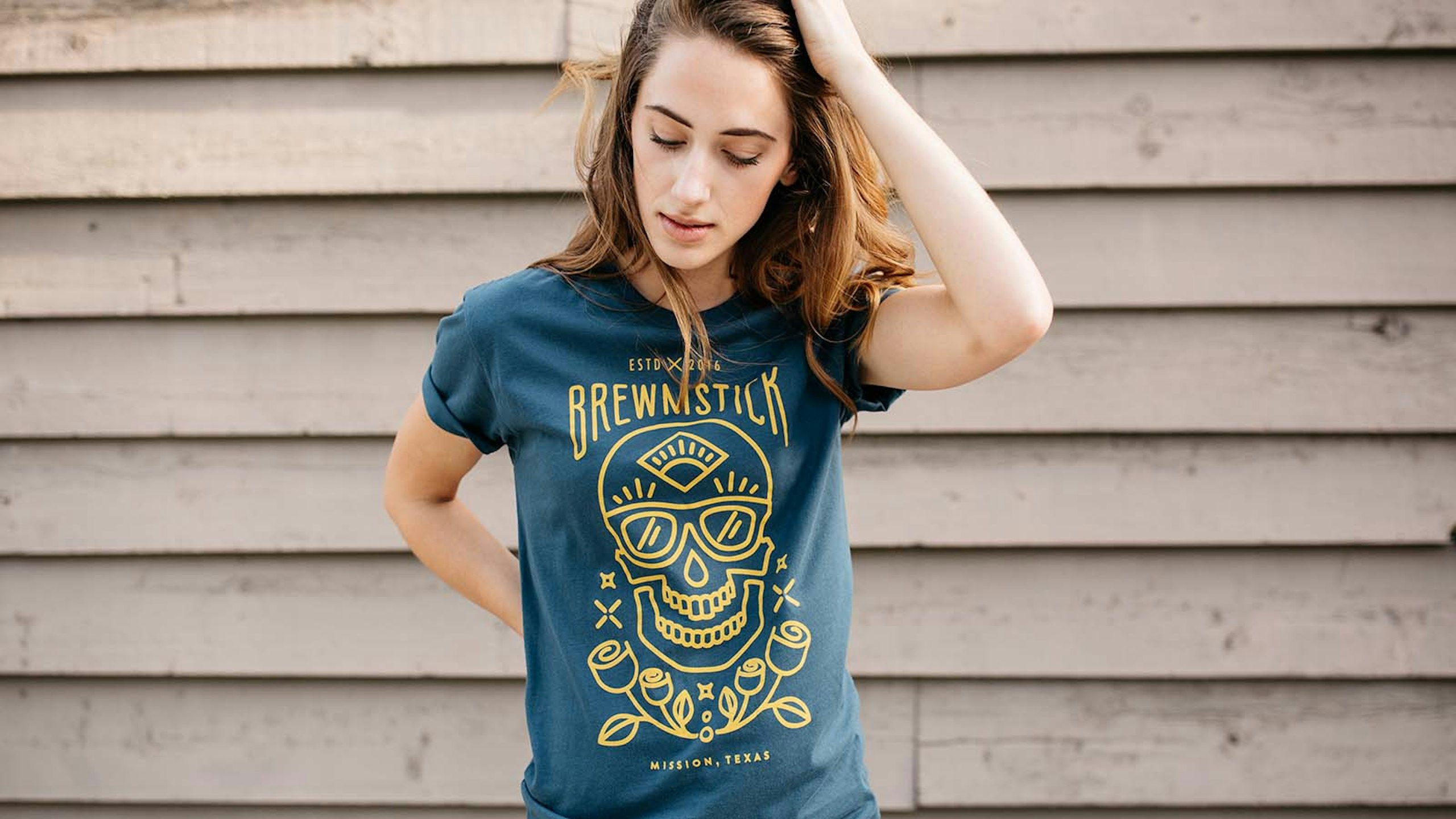 women wearing a green-blue shirt with a yellow outline of skull and roses