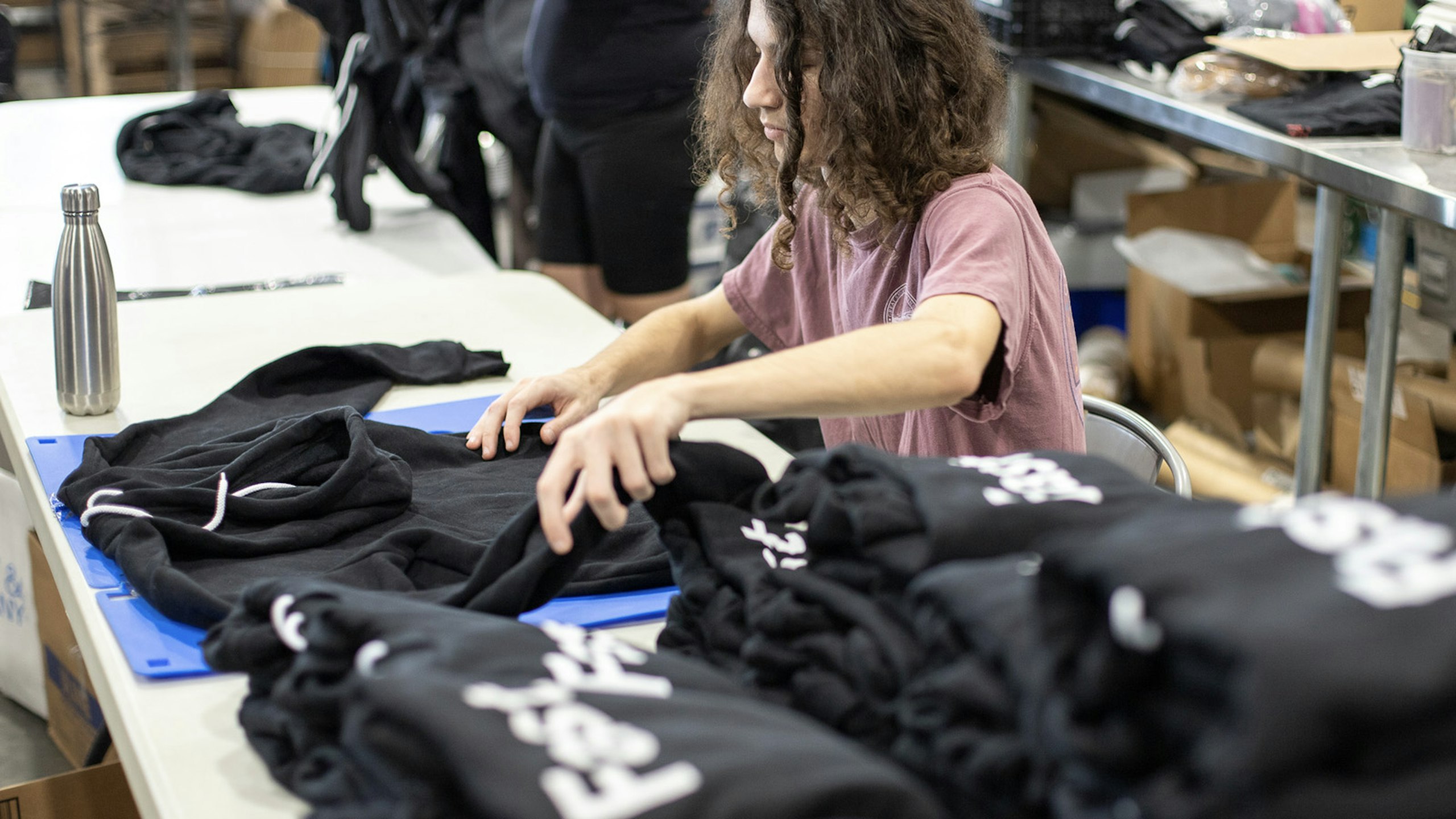 a person folding black hoodies