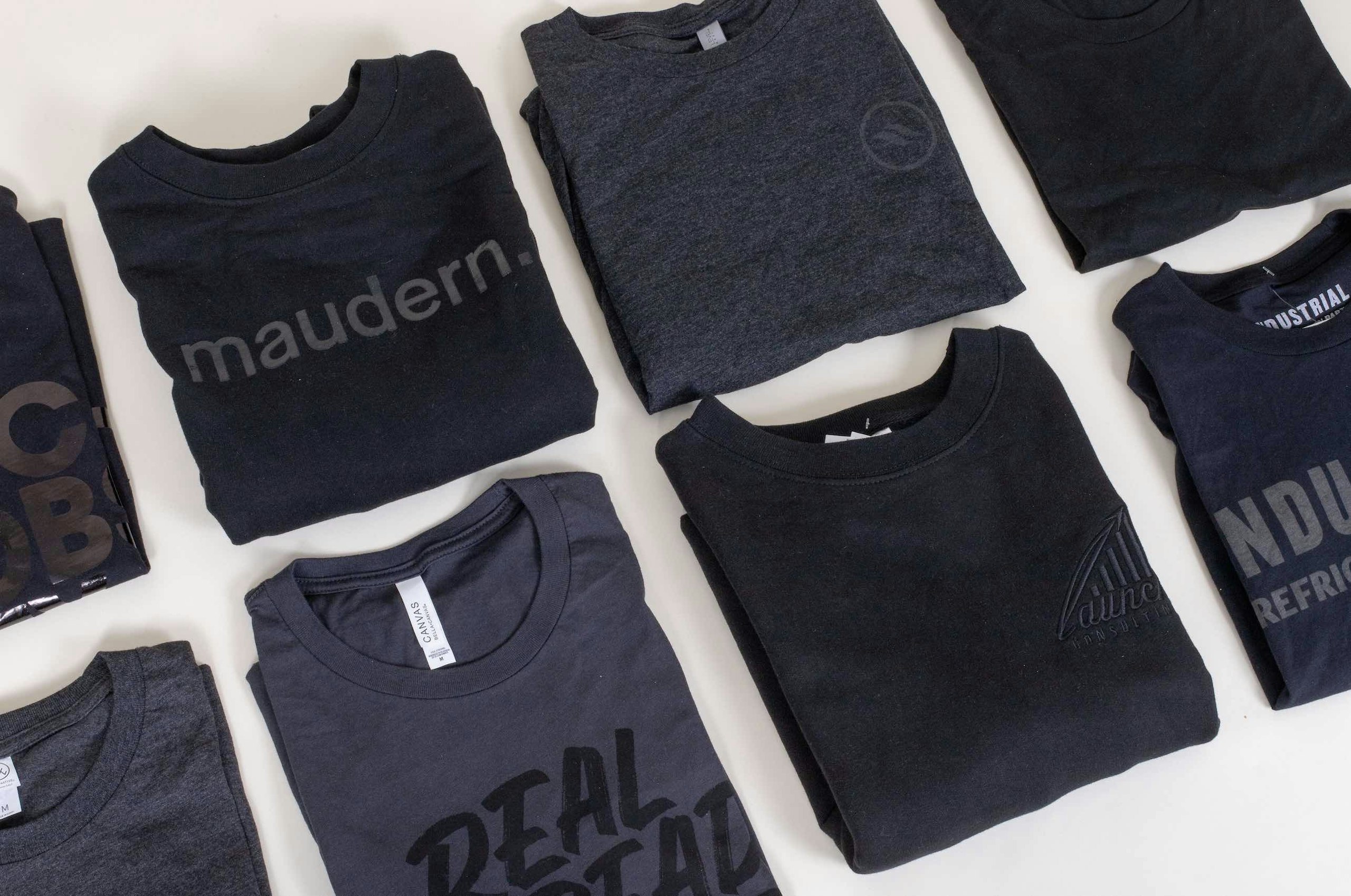 two rows of folded black t-shirts with black imprint