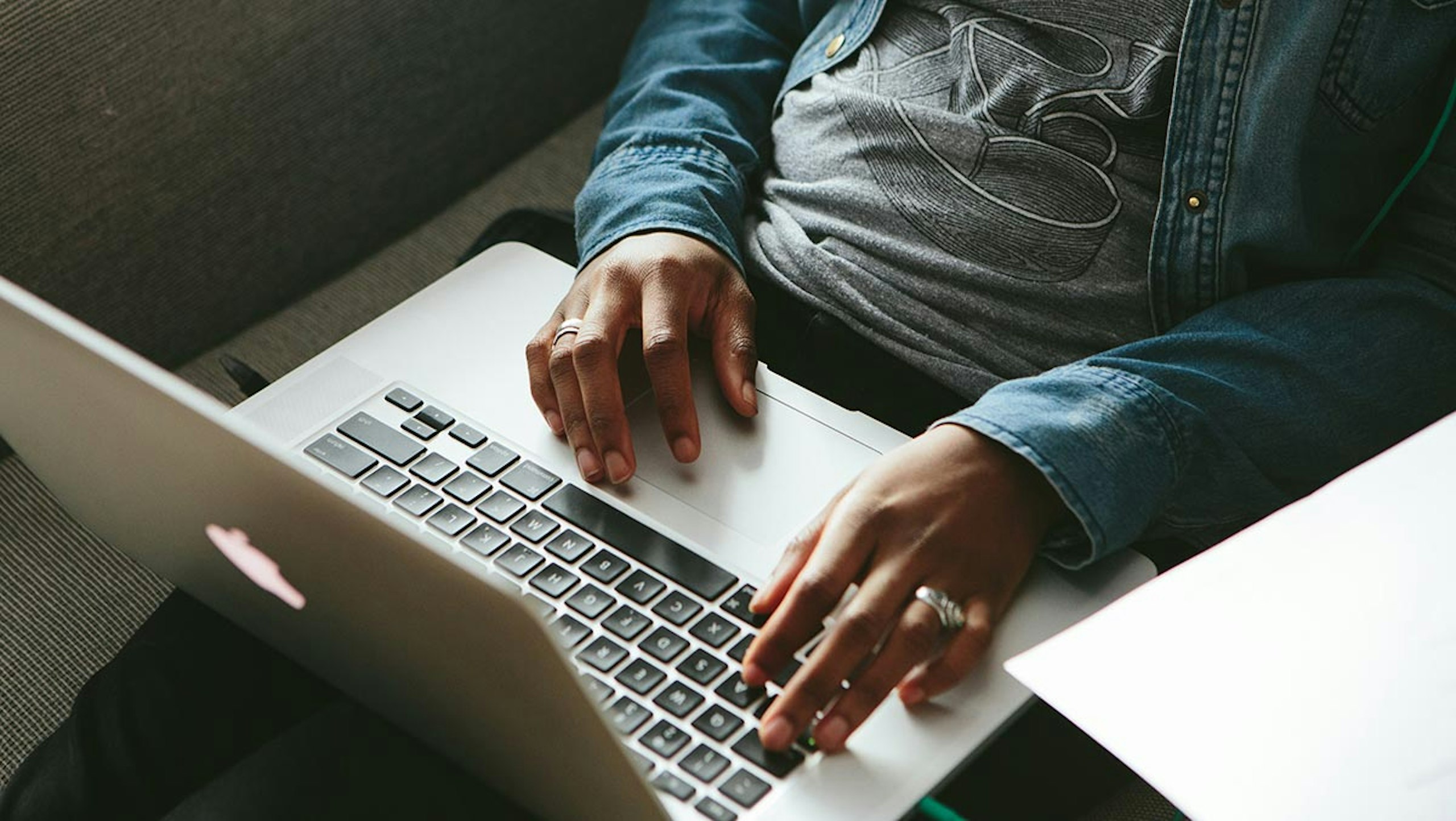 Am man wearing a t-shirt works on his couch with his laptop
