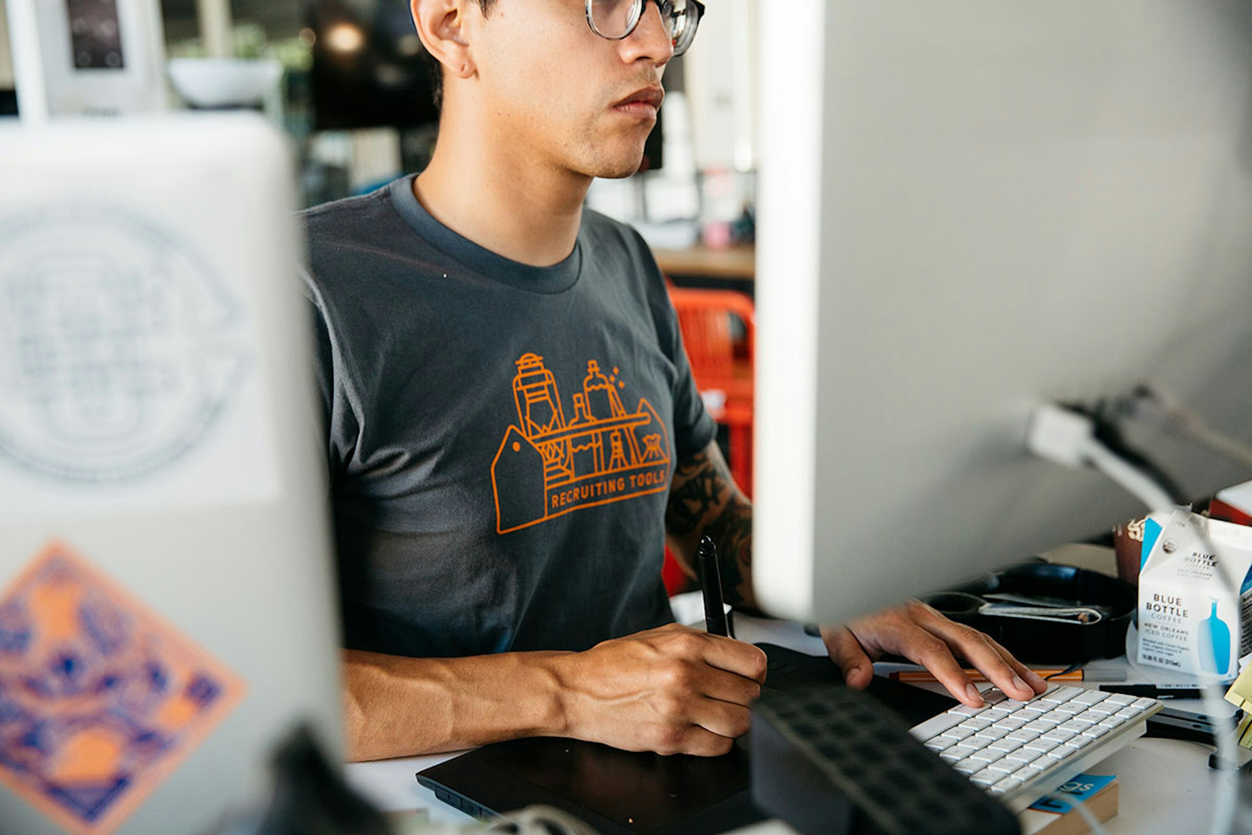 A man working for a remote job, while wearing a custom t-shirt that says "recruiting tools"