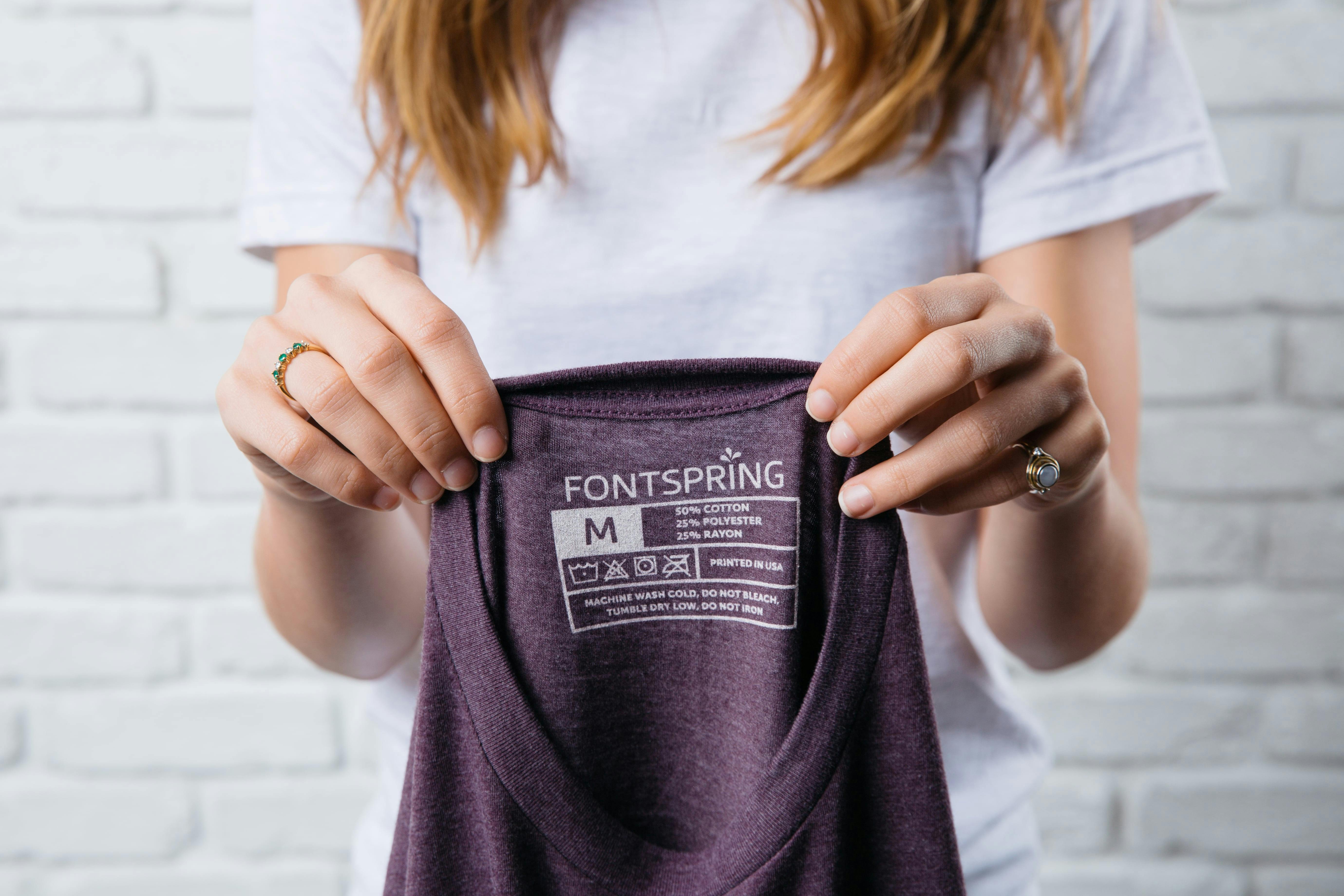 a women holding a dark grey t-shirt to show the printed tag