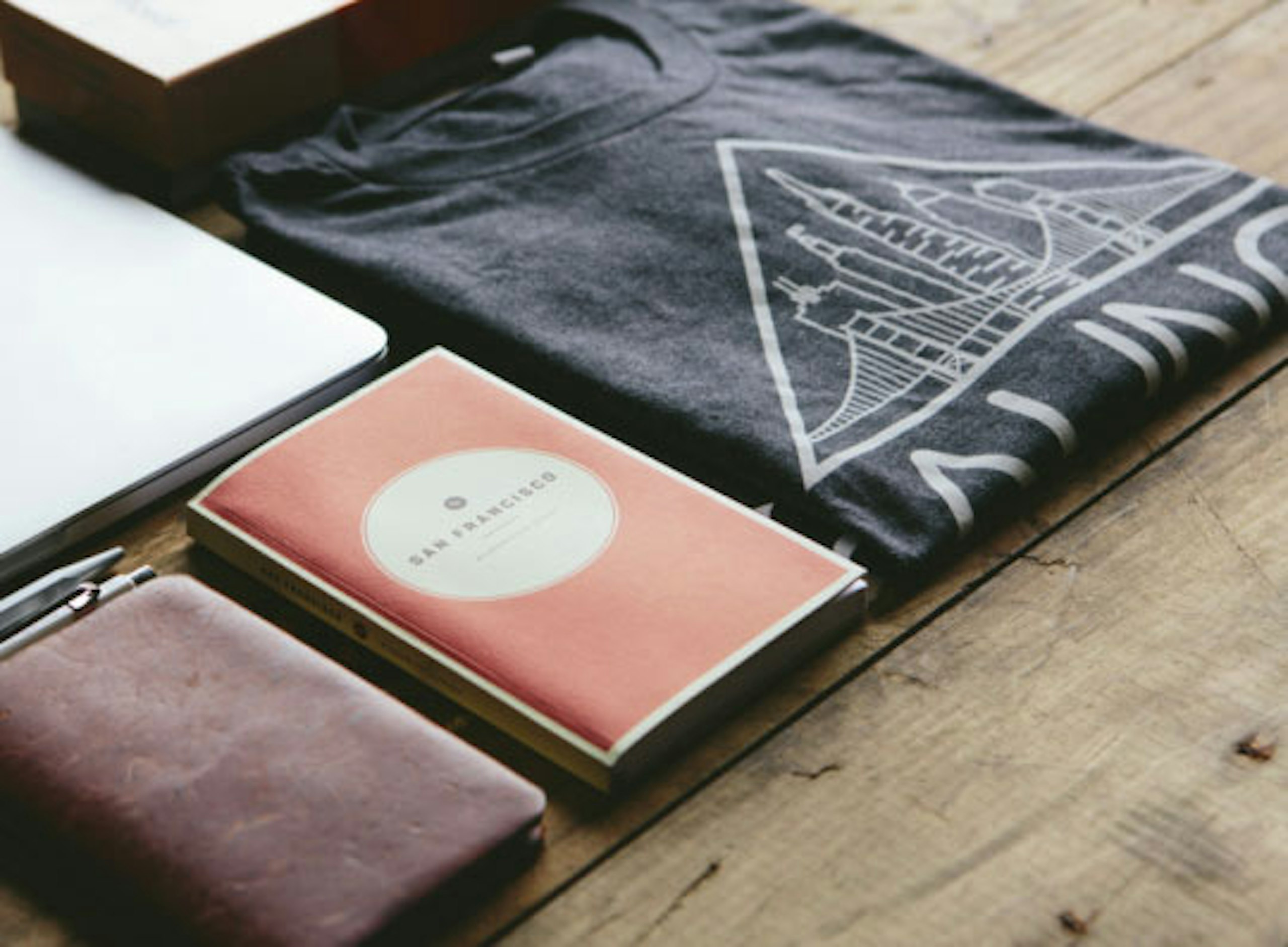 gray t-shirt folded with office stuff next to it