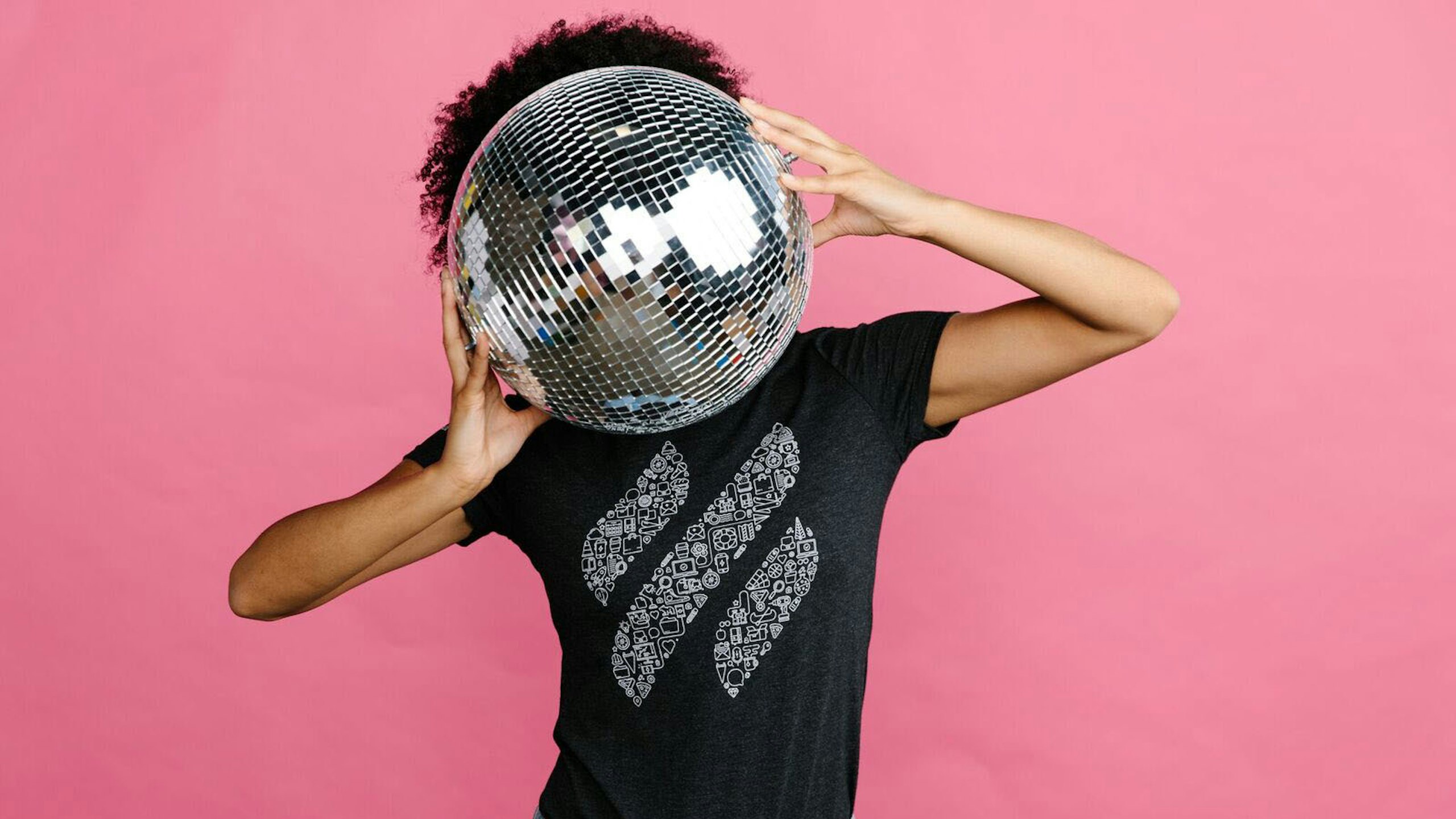 person holding a disco ball in front of a purple background