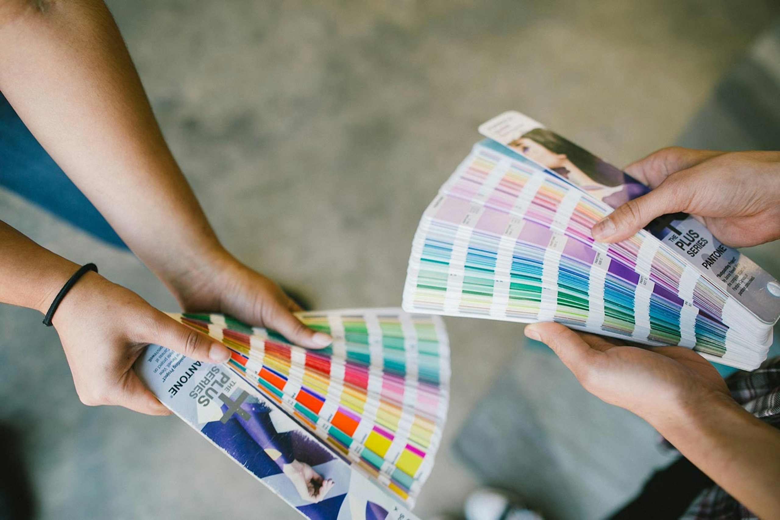 two people holding pantone books fanned out