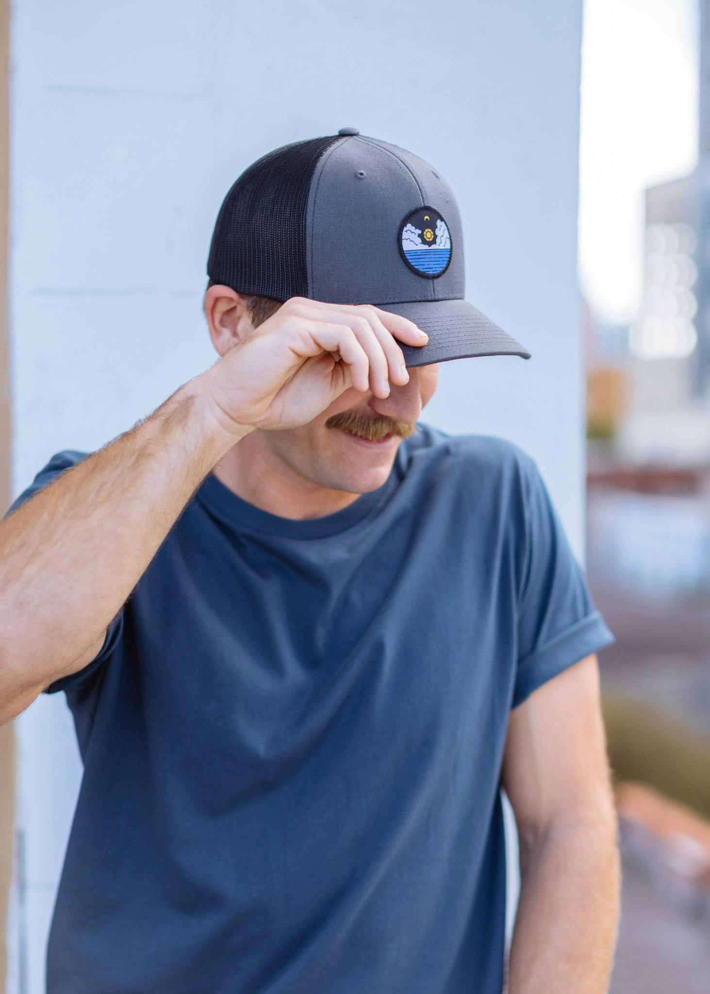 a man wears a hat with a sunset patch on it a man wears a hat with a sunset patch on it