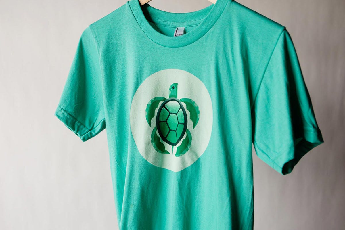 Green hanging t-shirt with green turtle logo on the front Green hanging t-shirt with green turtle logo on the front