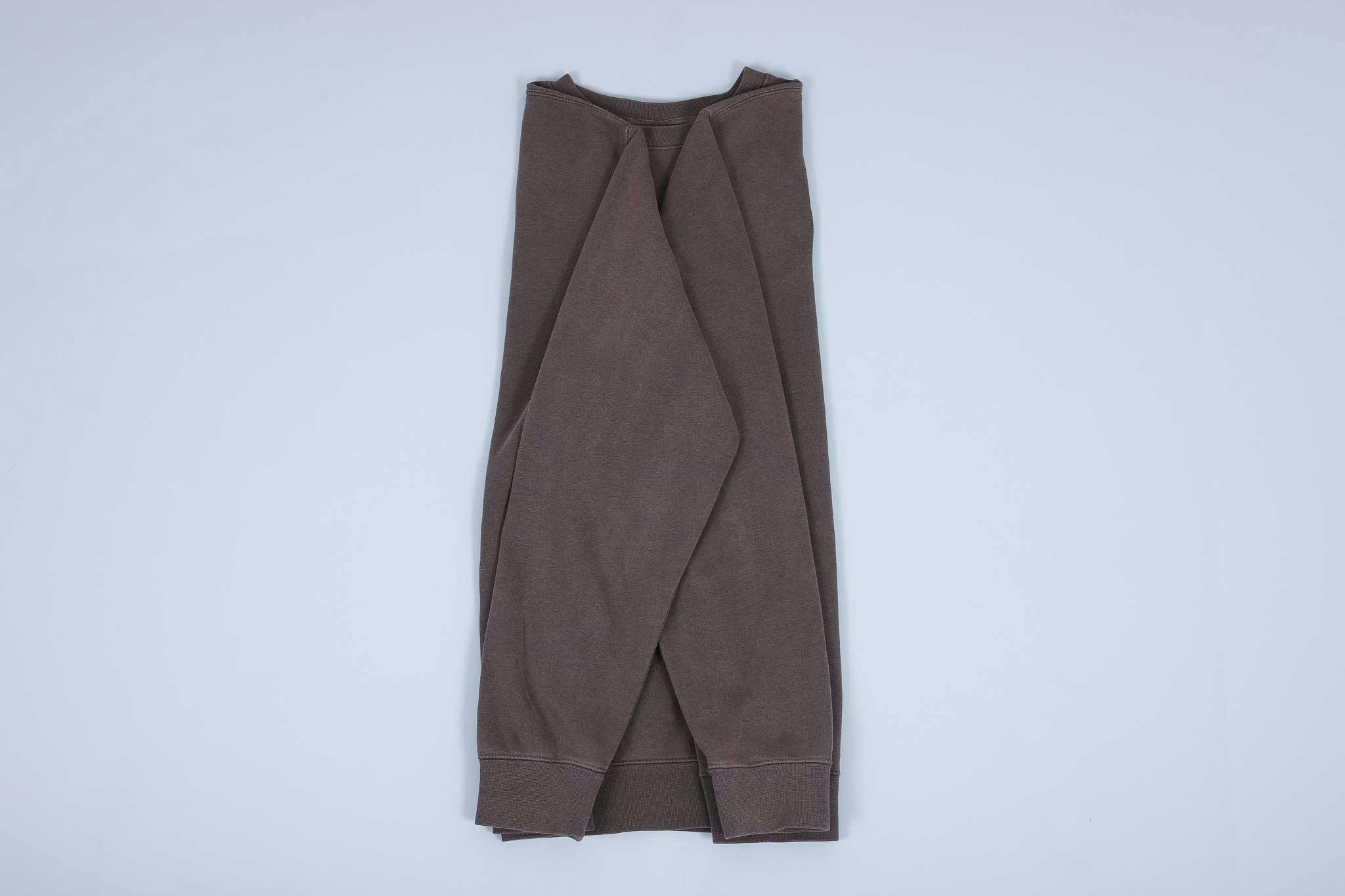 Grey sweater with both sleeves folded towards each other then away towards the hem Grey sweater with both sleeves folded towards each other then away towards the hem