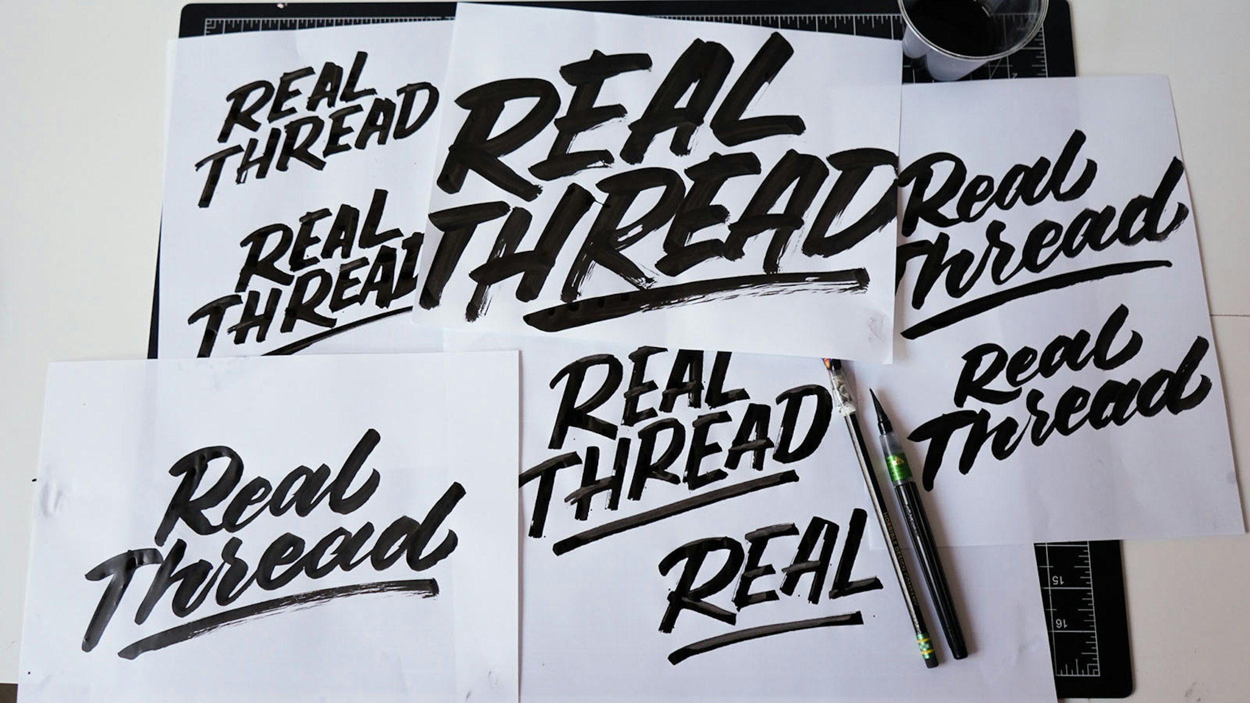 black brush font on white paper with the words real thread