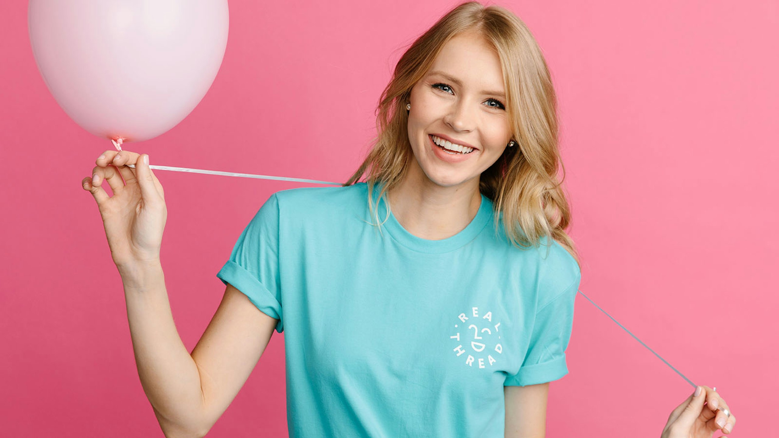 girl wearing a blue shirt in front of a pink background