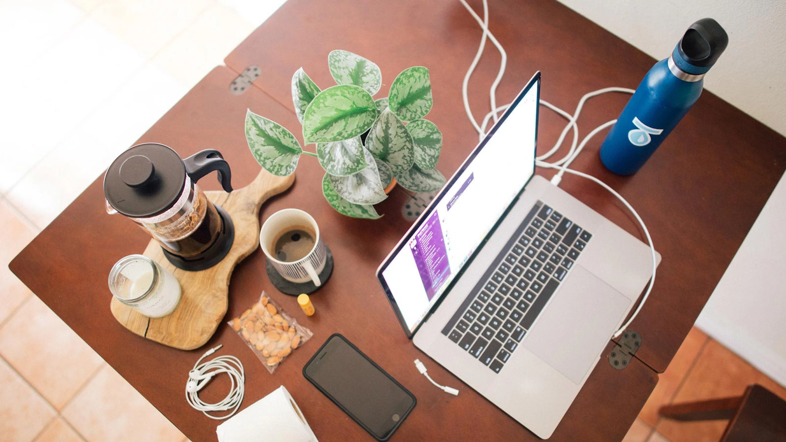 top-down view of a laptop on a desk with coffee and plant around it