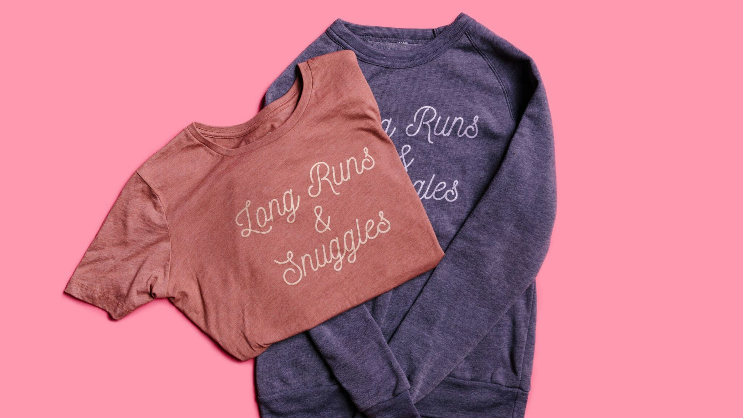red t-shirt and navy crewneck sweatshirt on a pink background