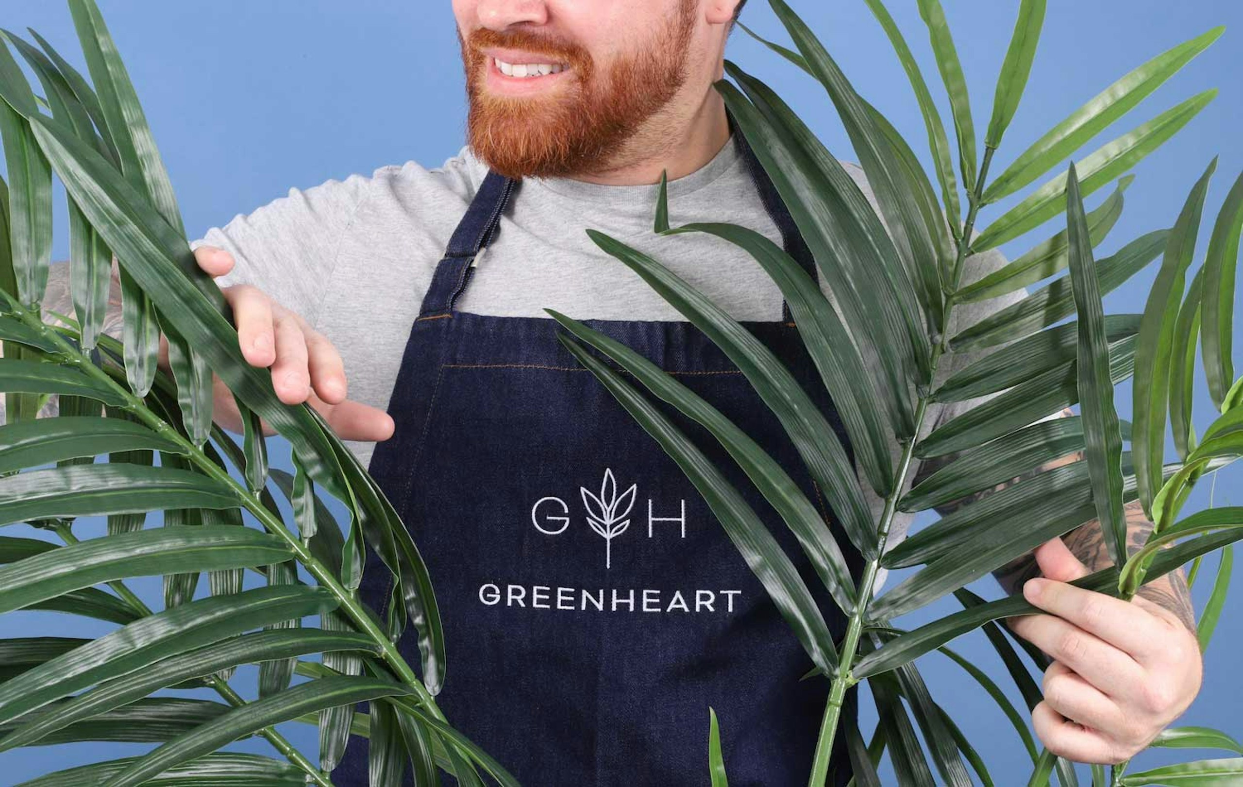 someone wearing a apron behind palm fronds 