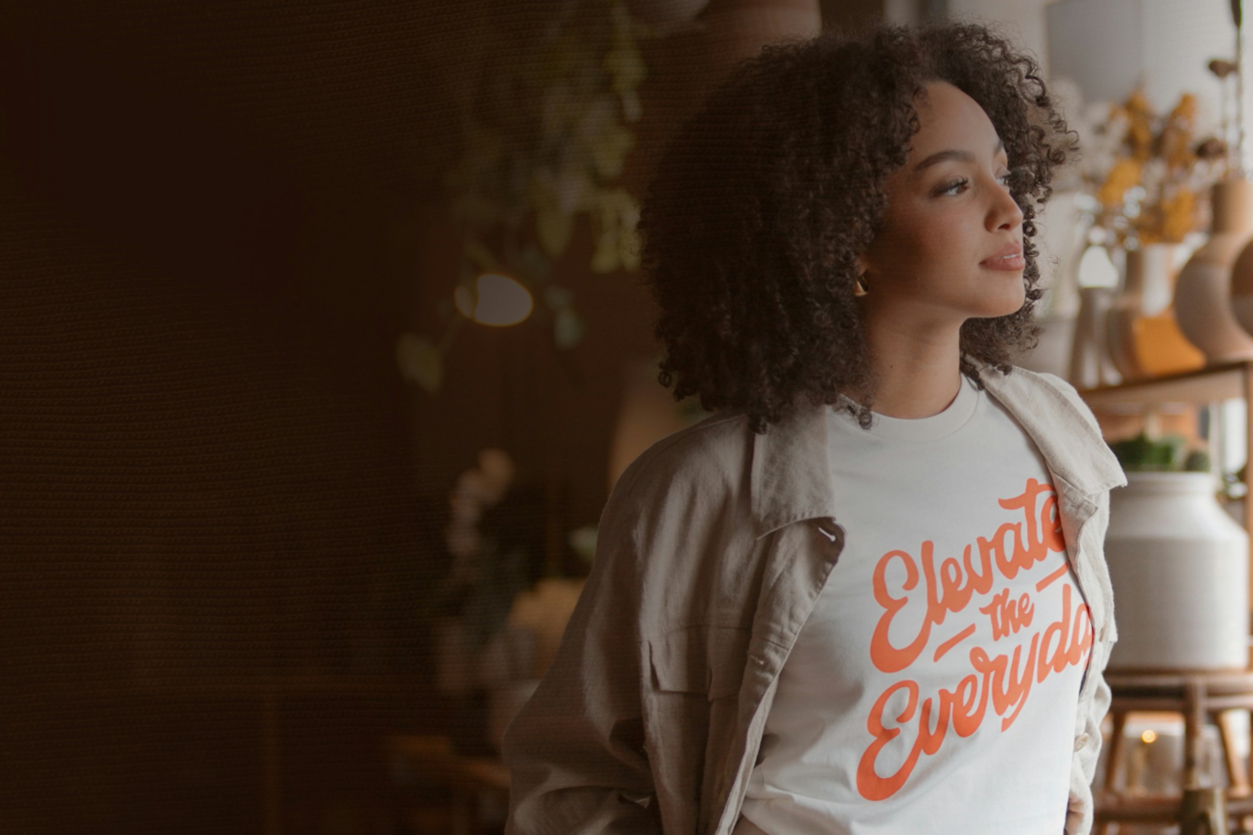 women wearing a white t-shirt with pick "elevate the everyday" words printed on it 