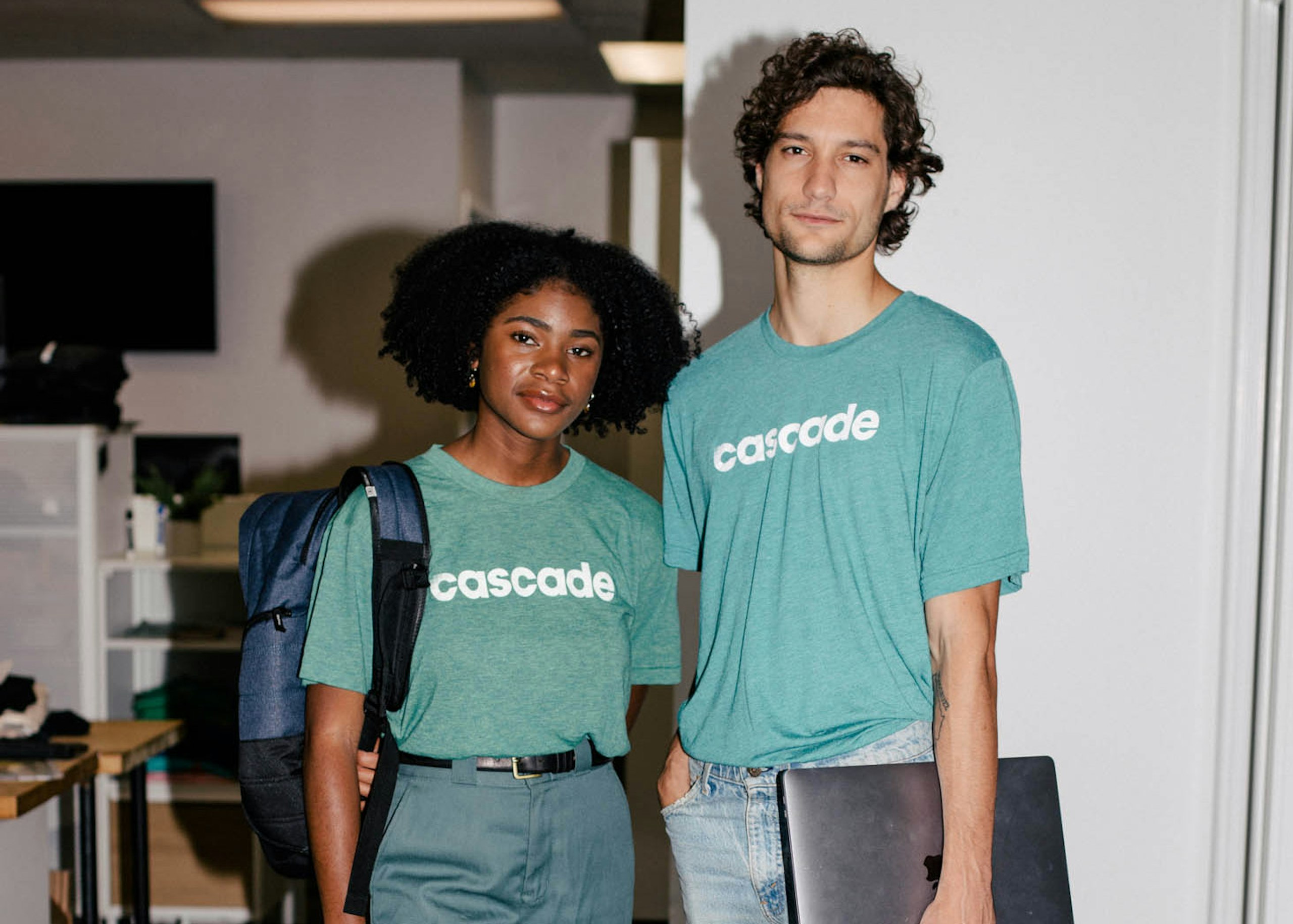 a women and man standing wearing teal t-shirts with the word cascade printed in white on them