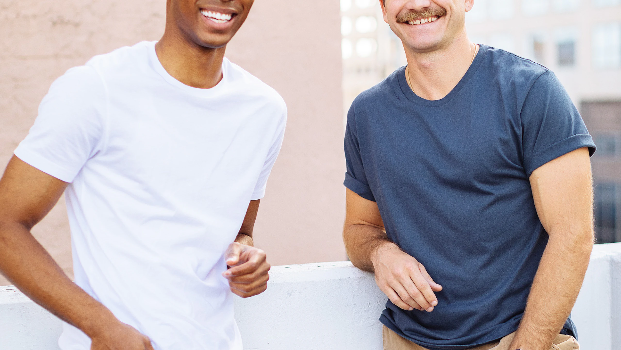 two men, one wearing a white tee and the other wearing a light navy tee