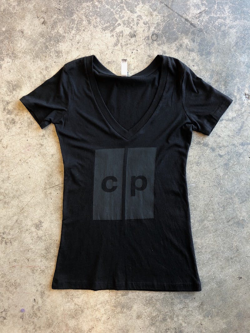 a black women's tee with black printed laying flat on the floor