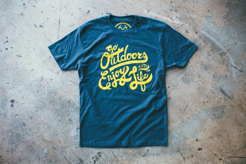 a deep blue tee with yellow script on a concrete floor