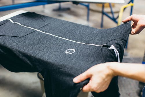 a heather grey zip-up hooding being pulled of a printing press