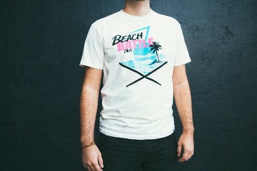 someone wearing a white tee with black, pink, and light blue beach print